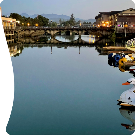 A serene river scene with a bridge and boats.