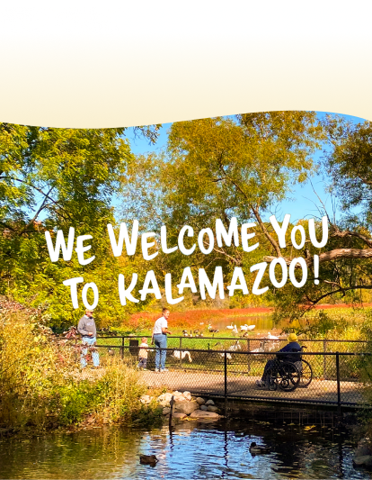 Accessible outdoor scene with a person in a wheelchair on a bridge, surrounded by trees, a pond, and birds, with two other people nearby. A text reads: 'We welcome you to Kalamazoo!'