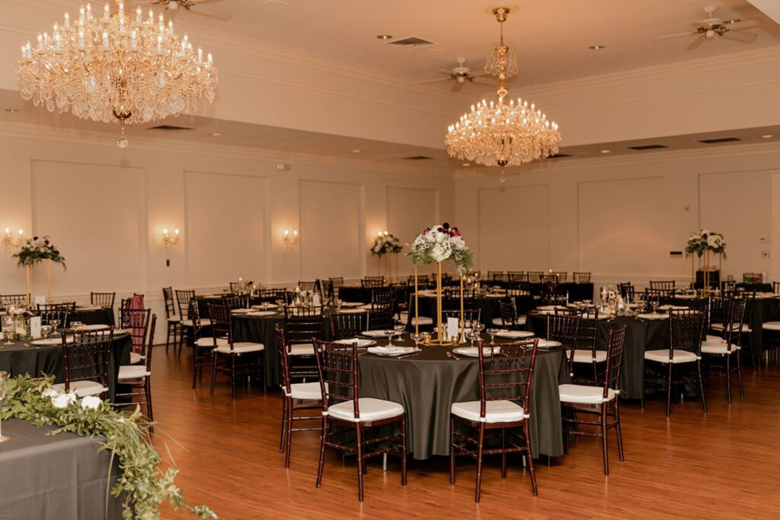 The reception hall at 173 Carlyle House, decorated with chandeliers and elegant table settings for the wedding celebration.