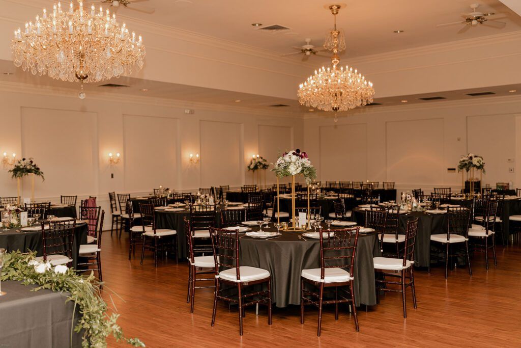 The reception hall at 173 Carlyle House, decorated with chandeliers and elegant table settings for the wedding celebration.