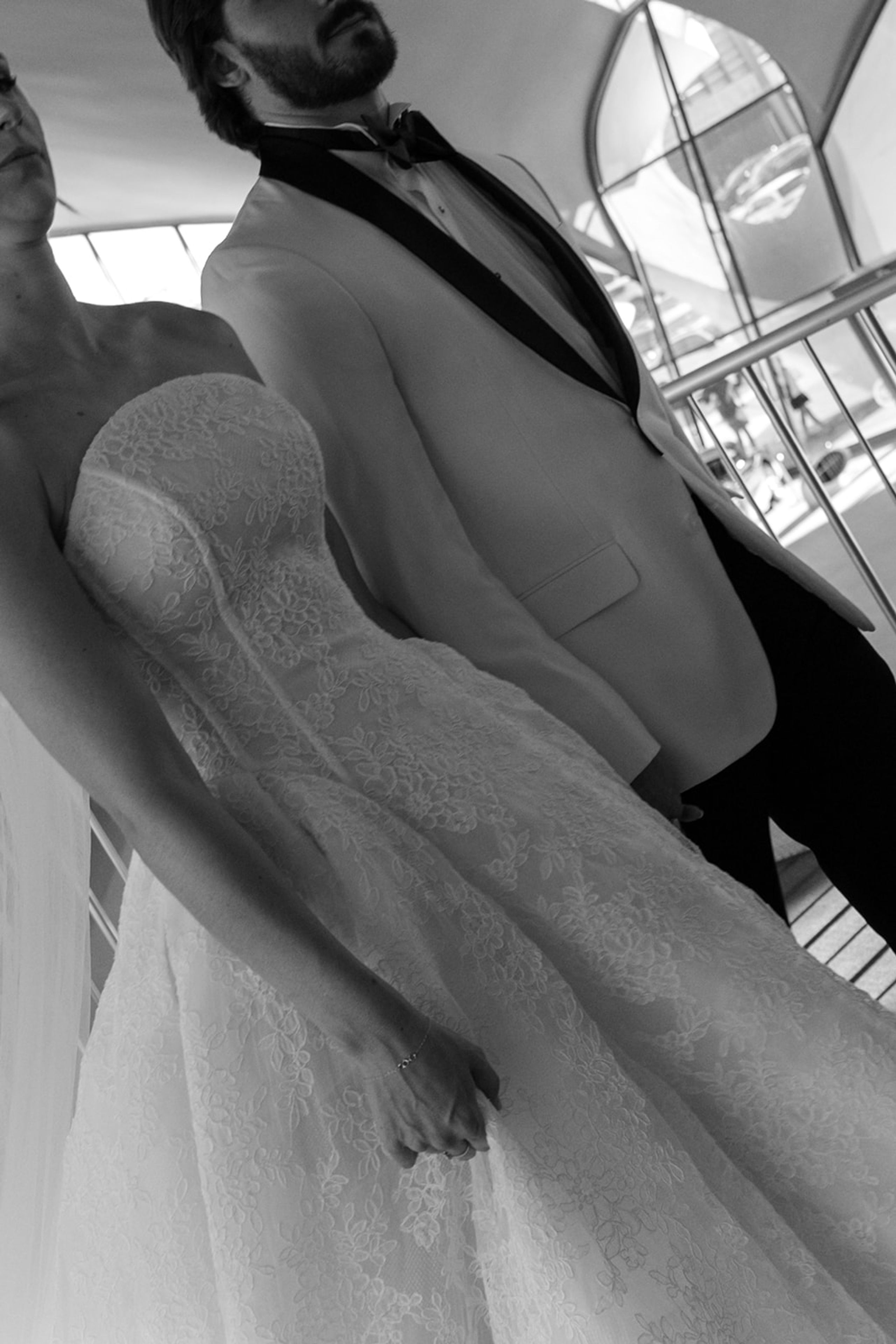 Black and white low angle photograph of a bride and groom holding hands at the TWA Hotel