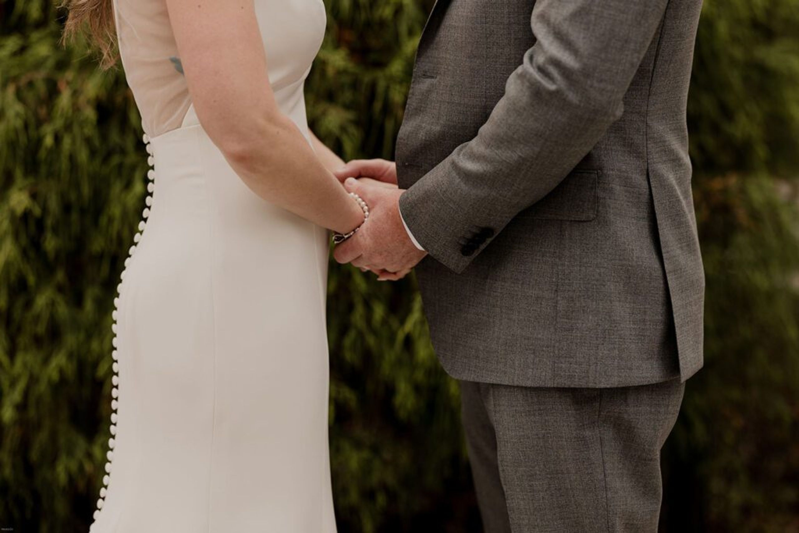 A close-up of Deb and Scott holding hands, showcasing their wedding rings and the intimacy of the moment.
