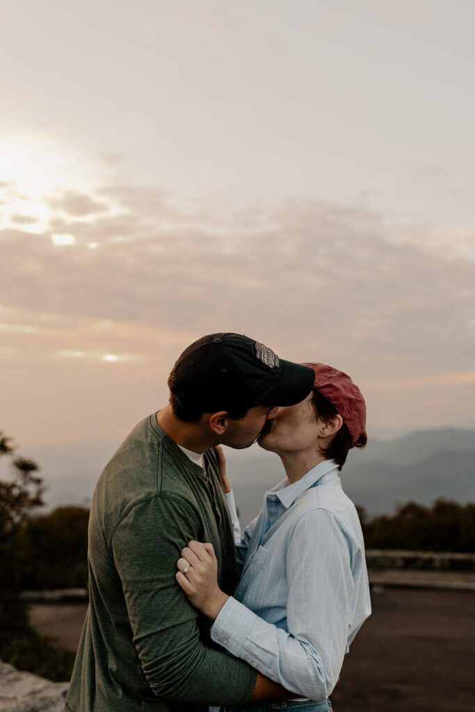 Couple kissing at sunset during their Craggy Gardens engagement session, capturing the golden hour glow.