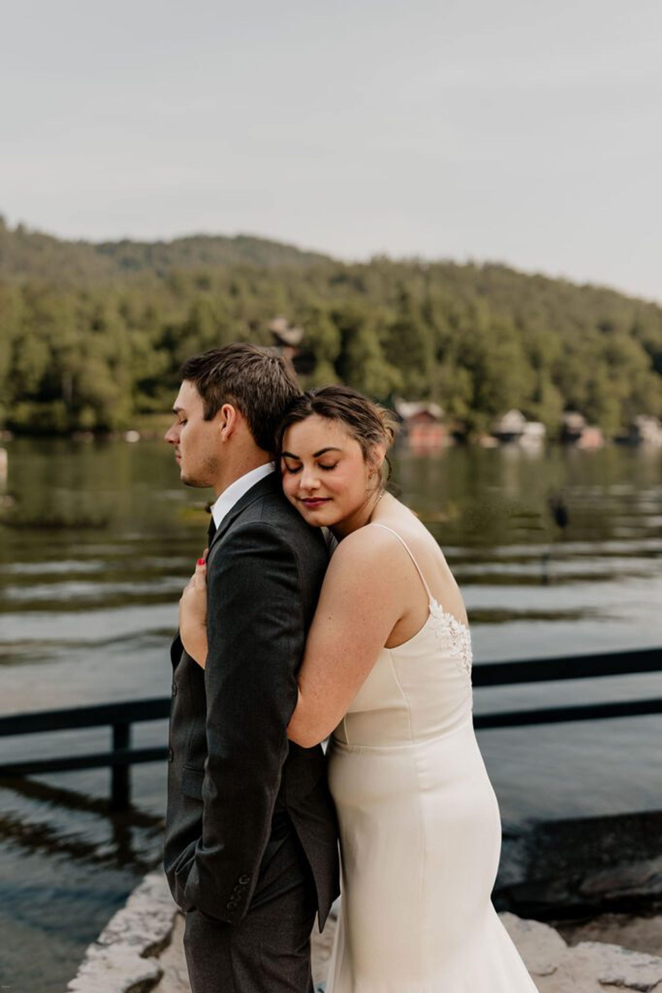 A series of candid moments from an Airbnb elopement, including the couple embracing by a lakeside, a close-up of their wedding attire on sandy ground, and the bride cutting a small wedding cake, reflecting the cozy and personal vibe of their celebration.

