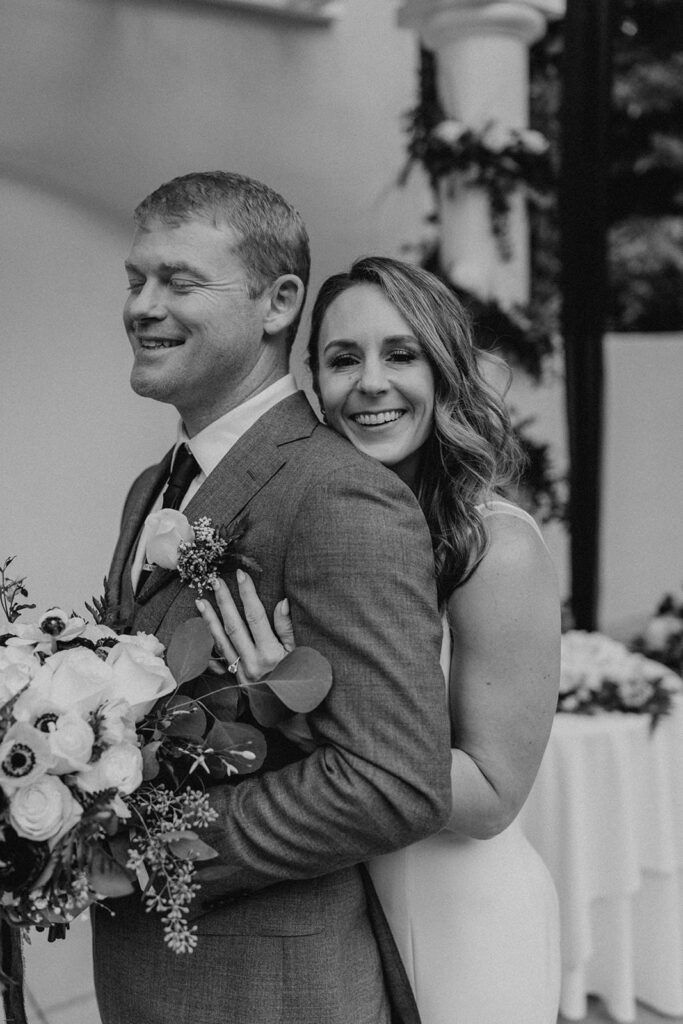 Deb hugs Scott from behind, both smiling as they stand together at 173 Carlyle House.