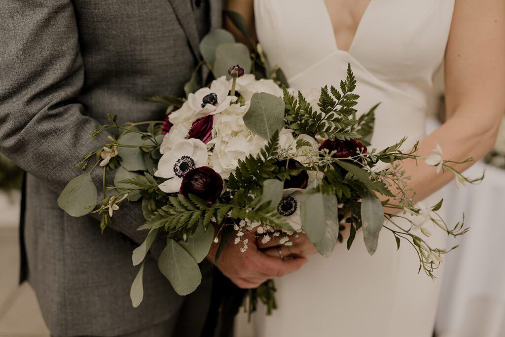 A close-up of Deb’s bouquet, featuring white and burgundy flowers, held during the wedding at 173 Carlyle House.