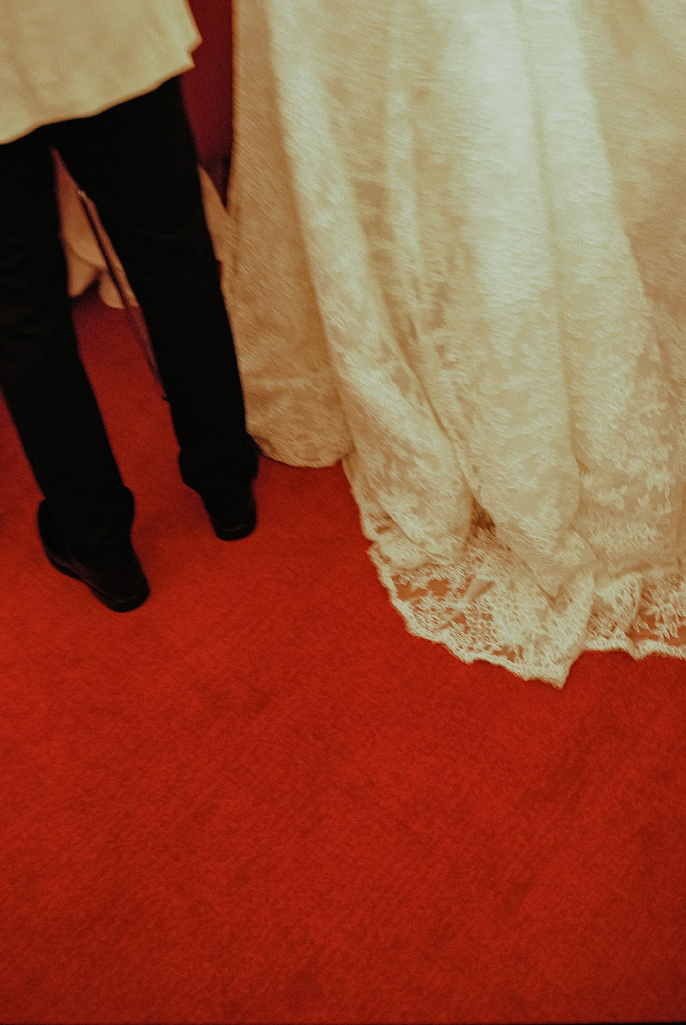 Lace hem of a wedding gown against the red carpet of the TWA Flight Center
