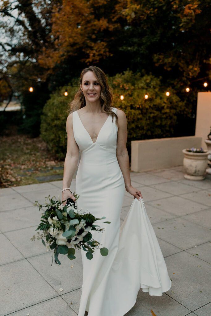 Deb gracefully holds her wedding dress as she walks outside at 173 Carlyle House.