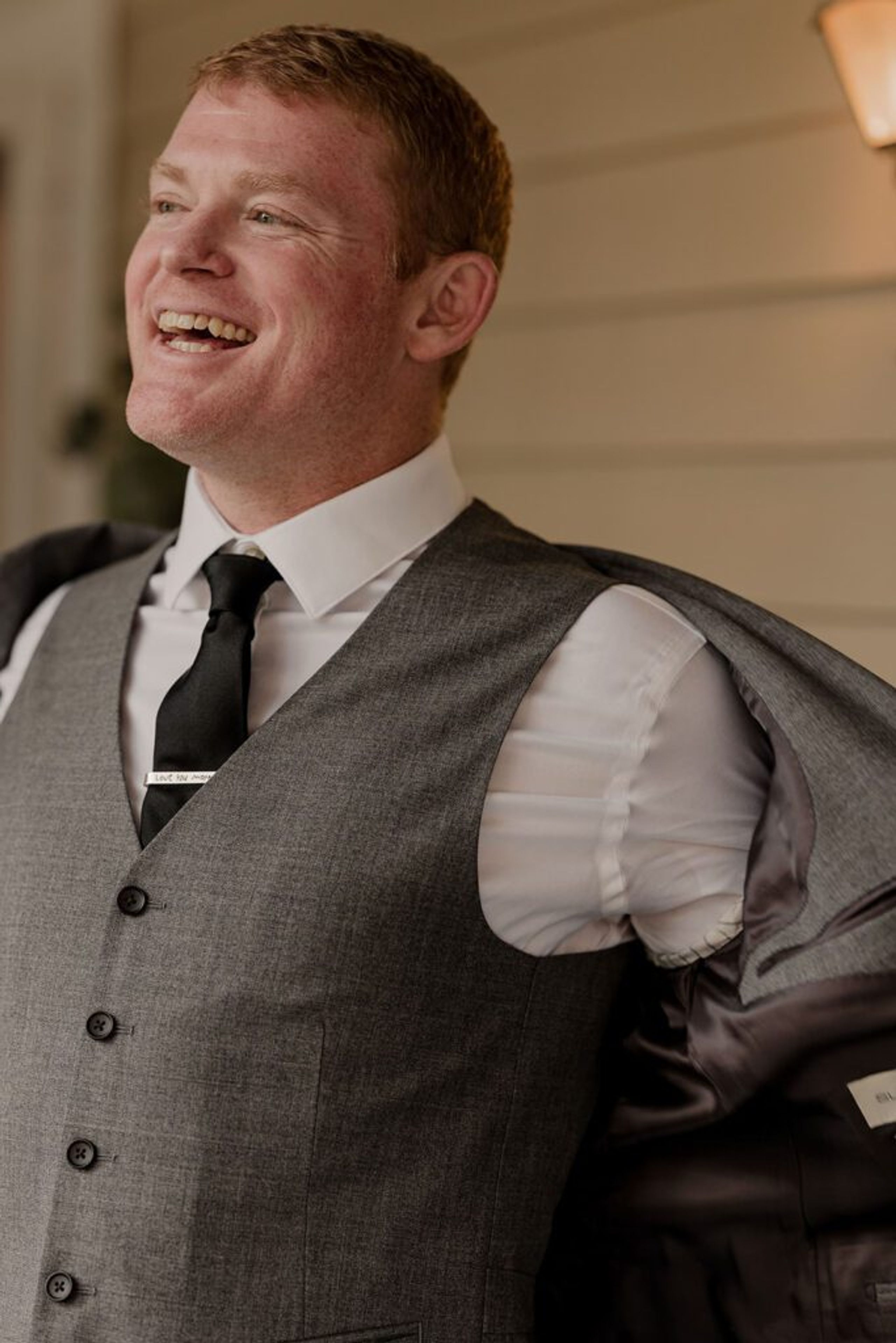 Scott smiles broadly as he adjusts his suit jacket while preparing for his wedding day.