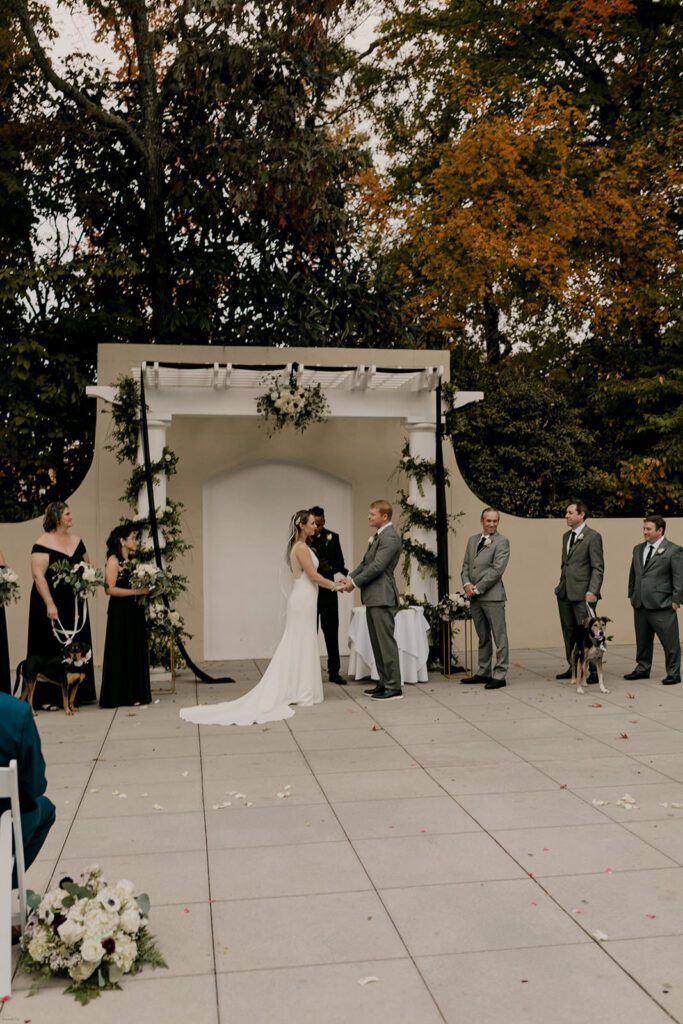 Scott and Deb exchange vows under a decorated arch at 173 Carlyle House, with guests watching