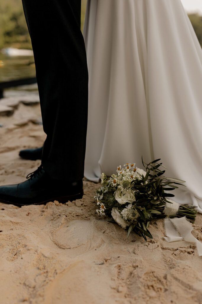 A series of candid moments from an Airbnb elopement, including the couple embracing by a lakeside, a close-up of their wedding attire on sandy ground, and the bride cutting a small wedding cake, reflecting the cozy and personal vibe of their celebration.