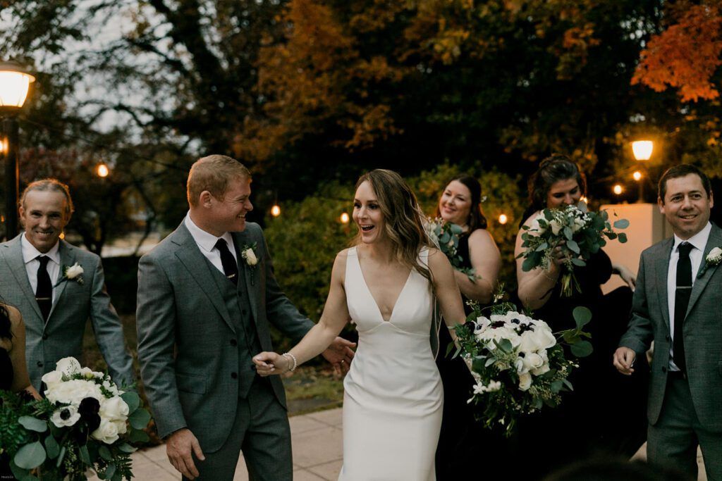 Deb walks hand in hand with Scott, smiling as they leave the celebration at 173 Carlyle House.