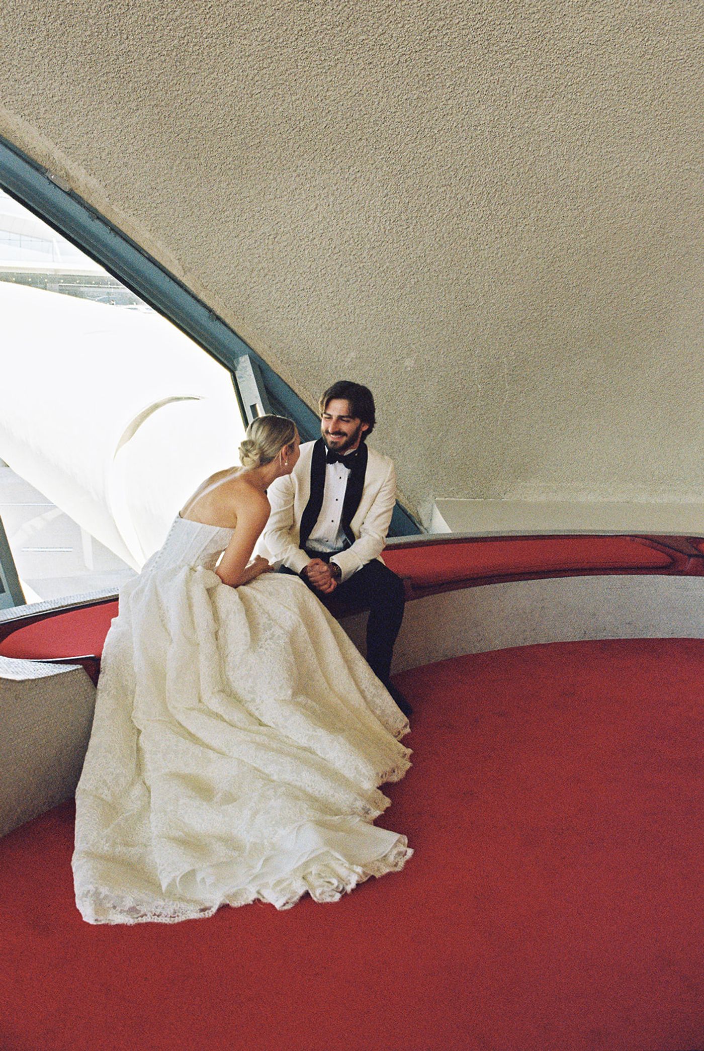 Bride and groom relaxing on red lounge seating in the TWA Flight Center terminal