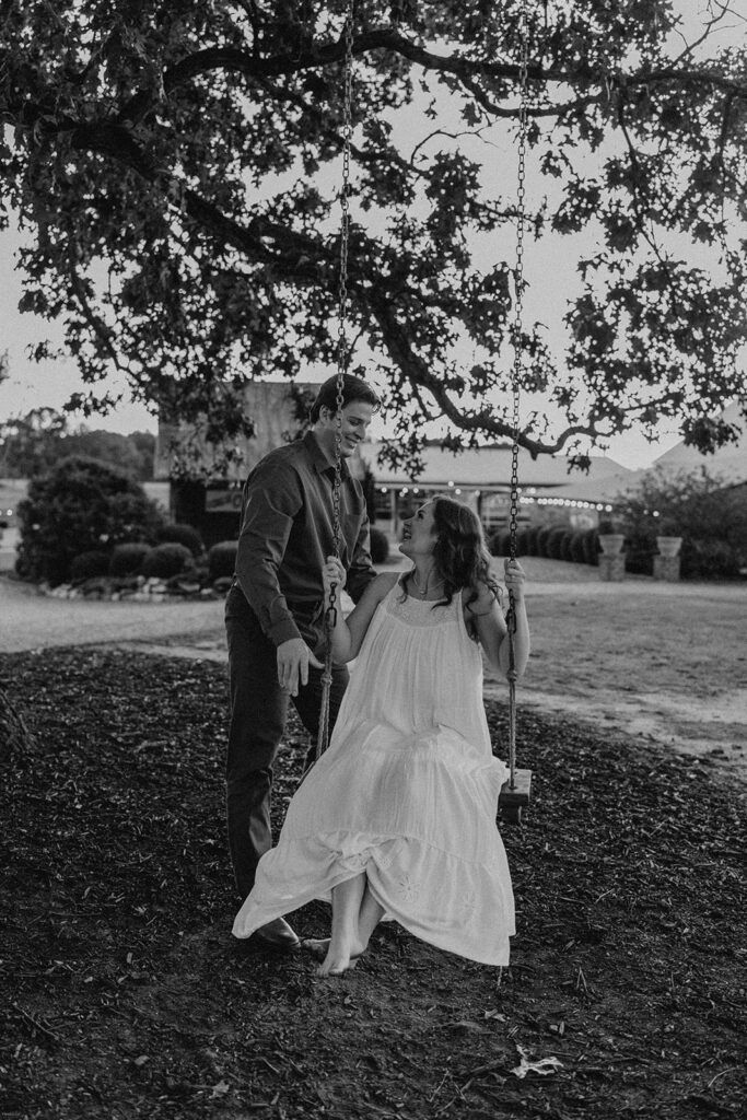 ake and Keaton on the rope swing at West Milford Farm in a black and white engagement session photo.