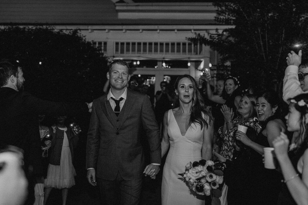 Scott and Deb walk hand in hand through a crowd of cheering guests after their wedding ceremony at 173 Carlyle House.