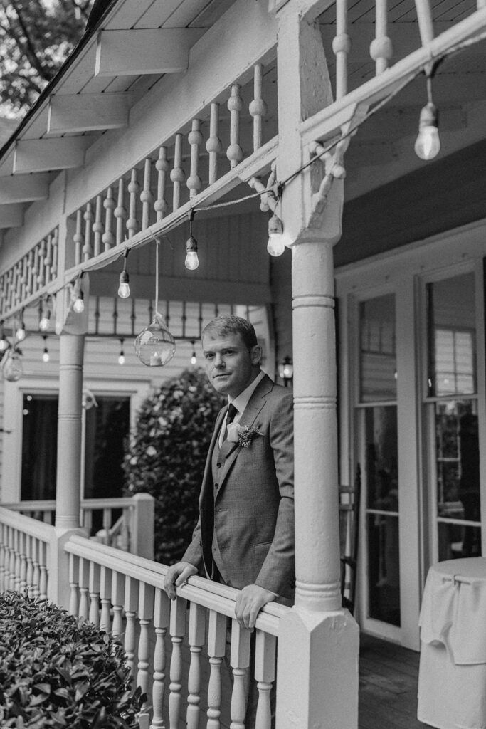 Scott stands on the porch at 173 Carlyle House, gazing thoughtfully ahead with string lights hanging above.