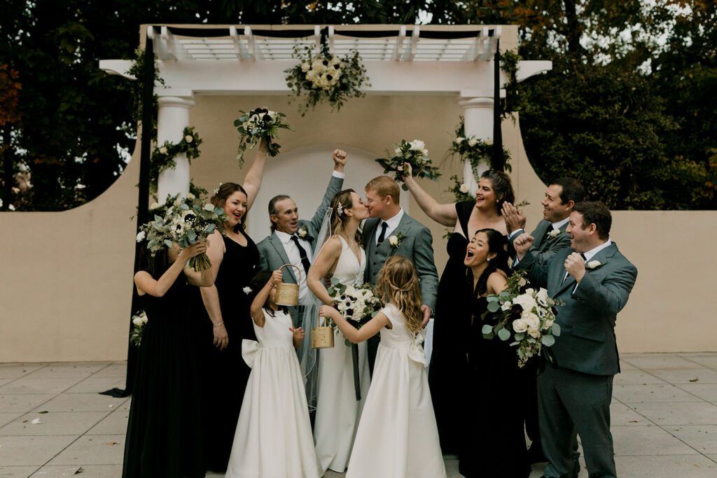 Scott and Deb celebrate with their bridal party, raising their hands in joy at 173 Carlyle House.