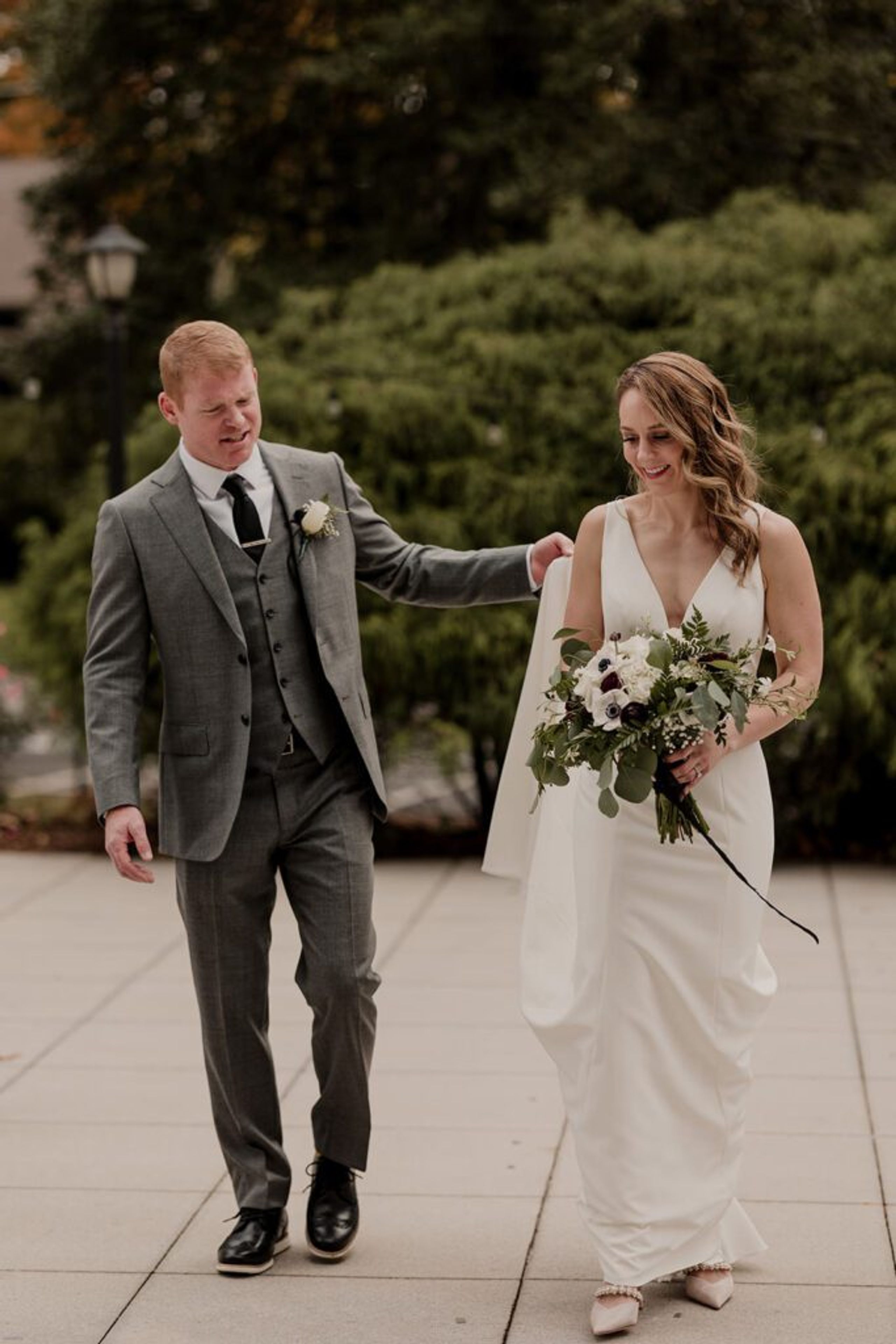 Scott and Deb walk hand in hand after their wedding ceremony, with Deb holding a beautiful bouquet.