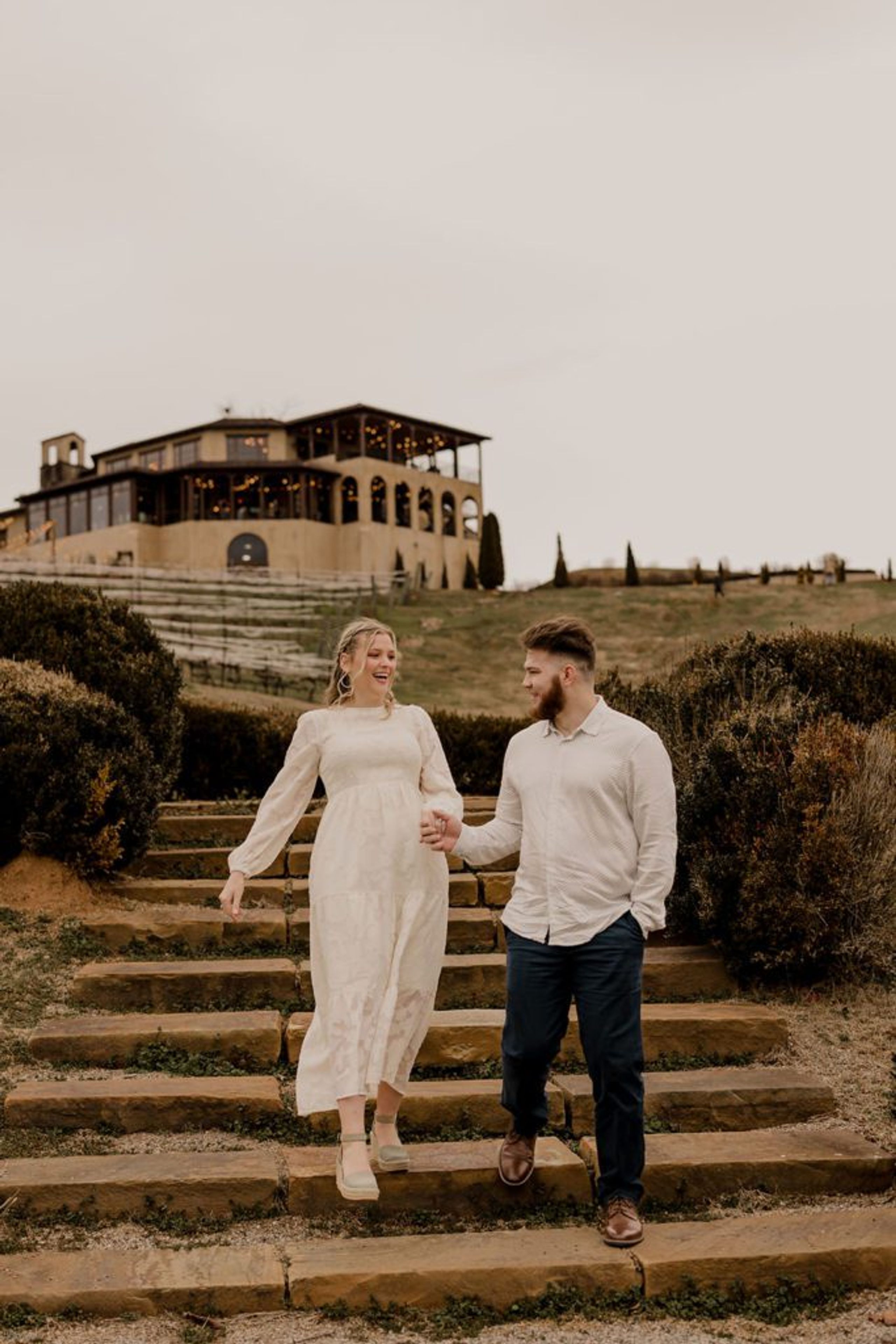 Taylor and Guillermo walking down stone steps at Monteluce Winery with the Tuscan-style building in the background.