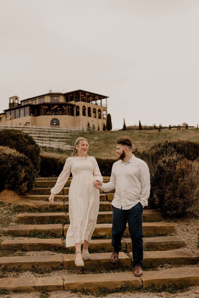 Taylor and Guillermo walking down stone steps at Monteluce Winery with the Tuscan-style building in the background.