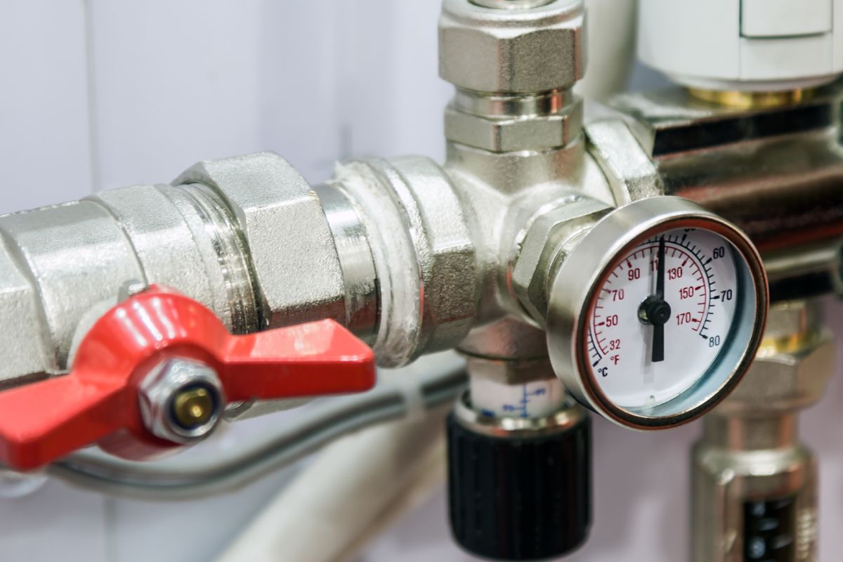 A tempering valve and temperature gauge on plumbing pipework