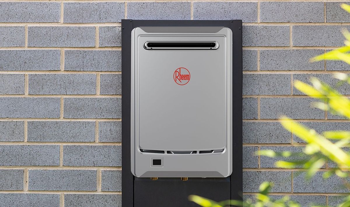 A Rheem continuous flow hot water system mounted on a brick wall