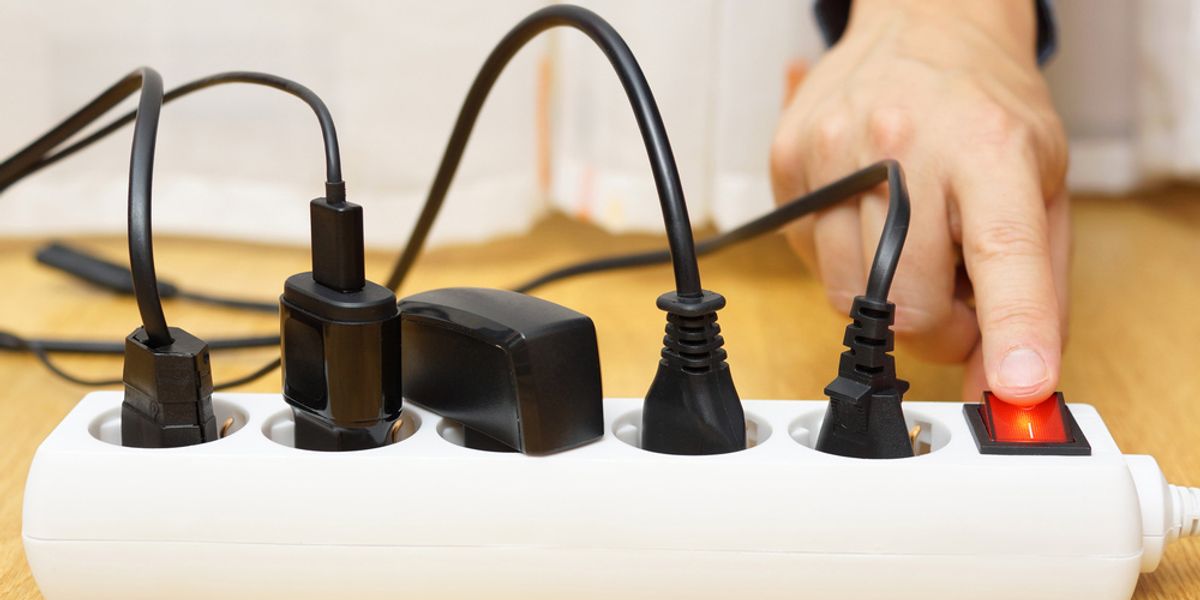 A hand switching on a powerboard loaded with several plugs
