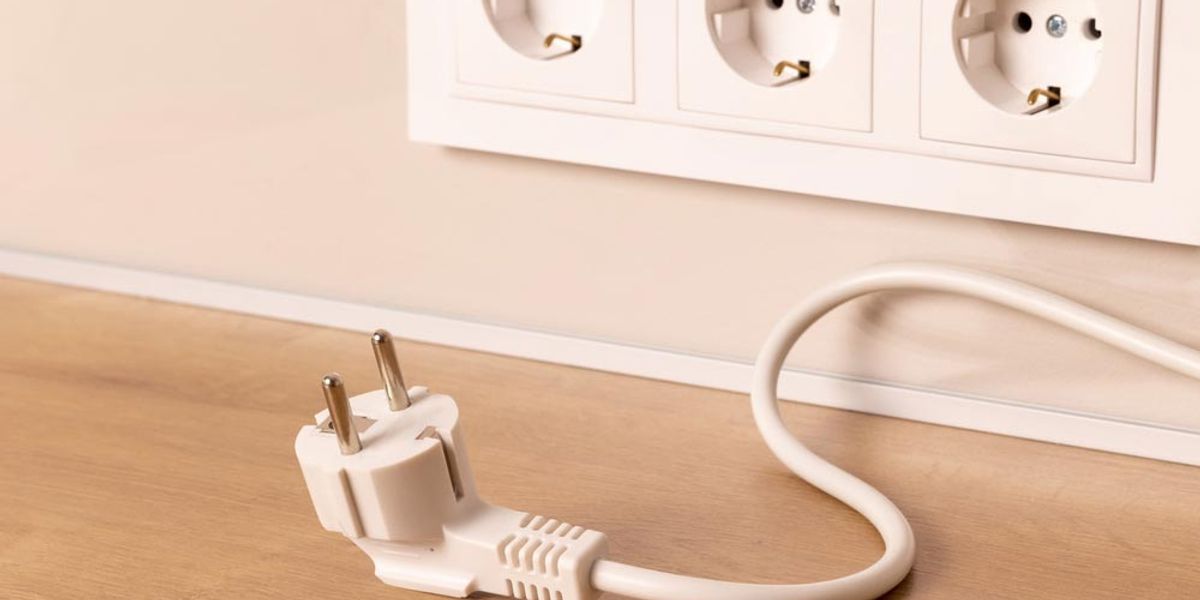 A power lead unplugged and lying below a row of wall outlets