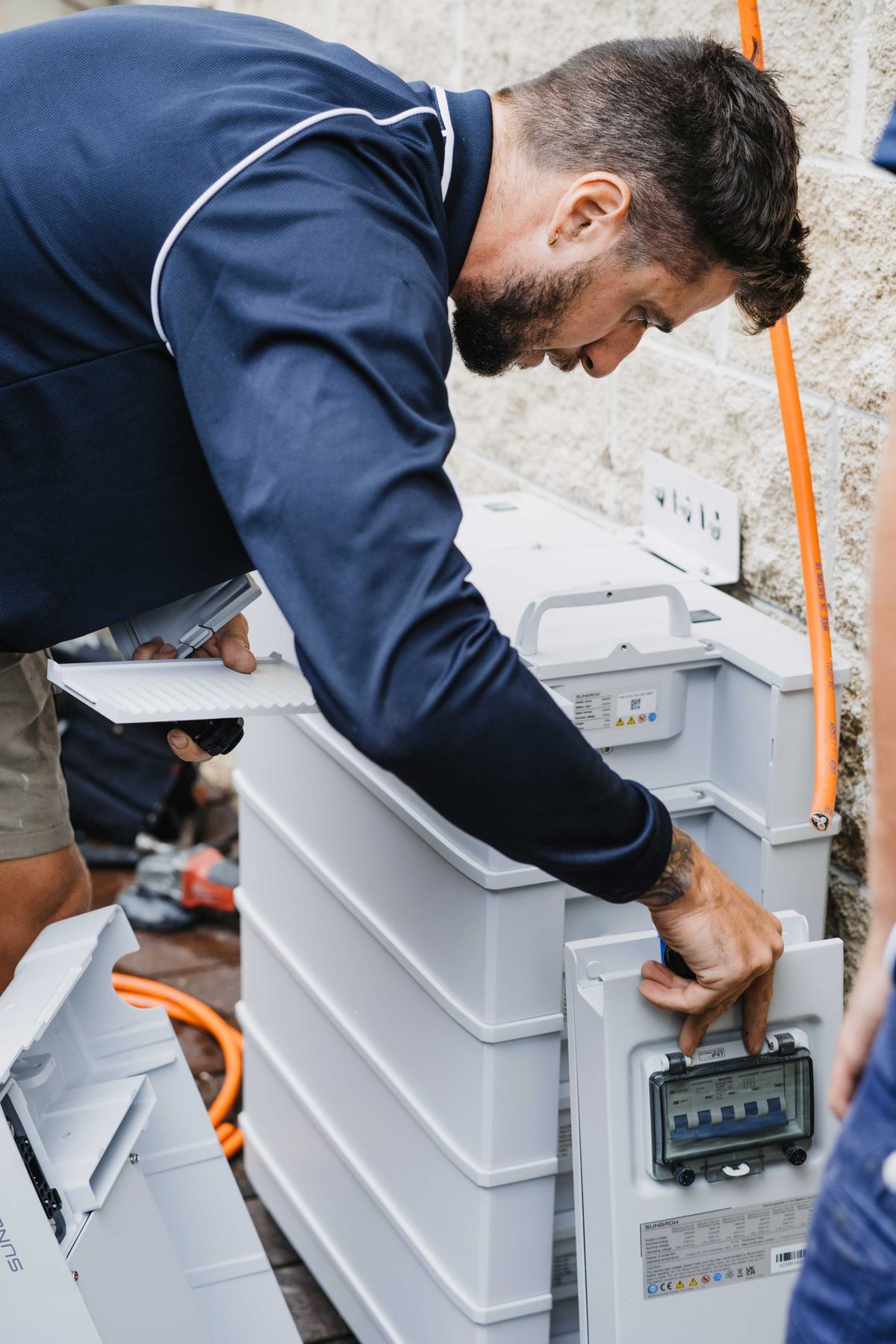 A technician connecting cables to a stacked home battery system