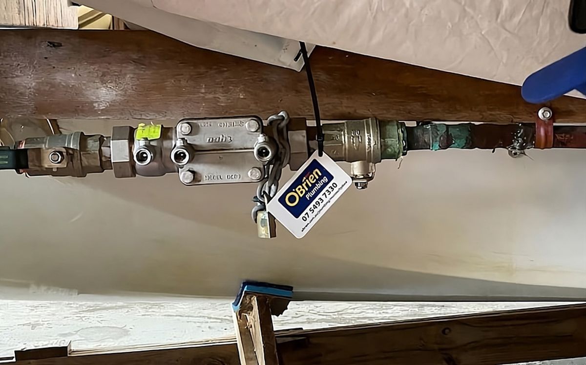 A backflow prevention device under a building, carrying an O’Brien service tag