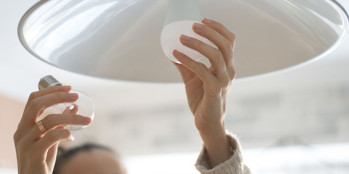 A person changing the globe in a pendant light shade