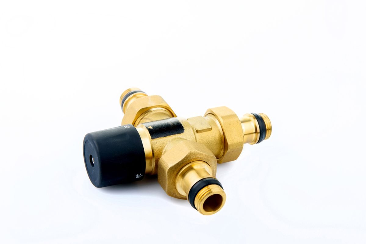 A brass thermostatic mixing valve with a black adjustment cap