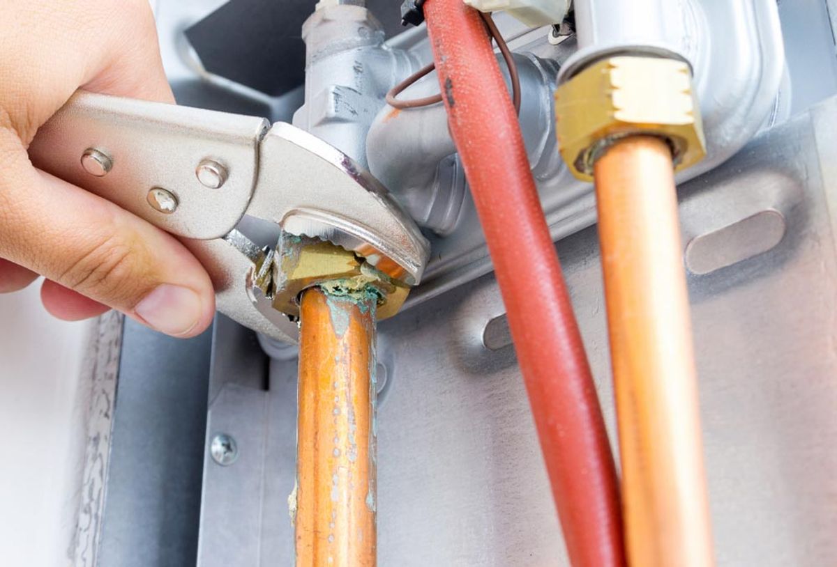 A hand tightening a fitting on copper pipework with a spanner