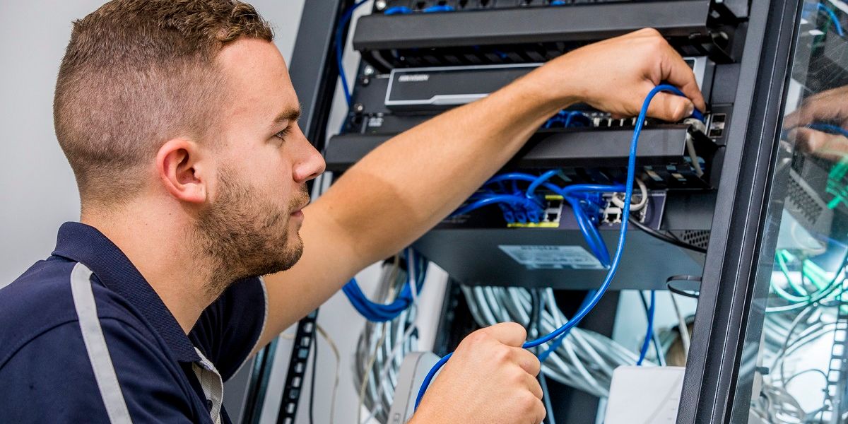A technician patching network cables in a communications rack