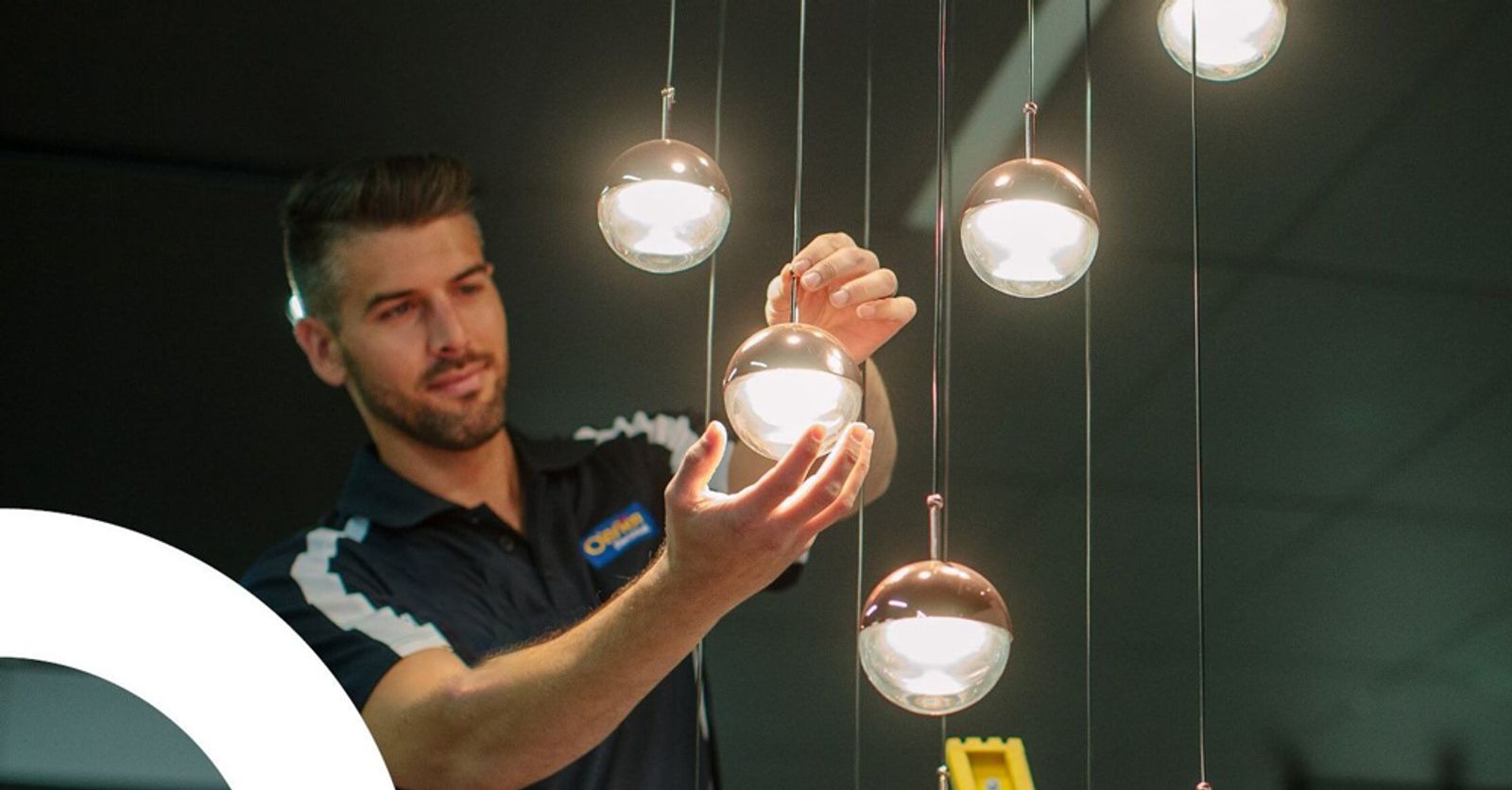 An electrician adjusting a cluster of hanging pendant globes