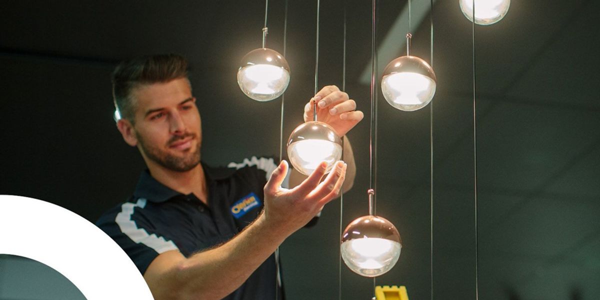 An electrician adjusting a cluster of hanging pendant globes