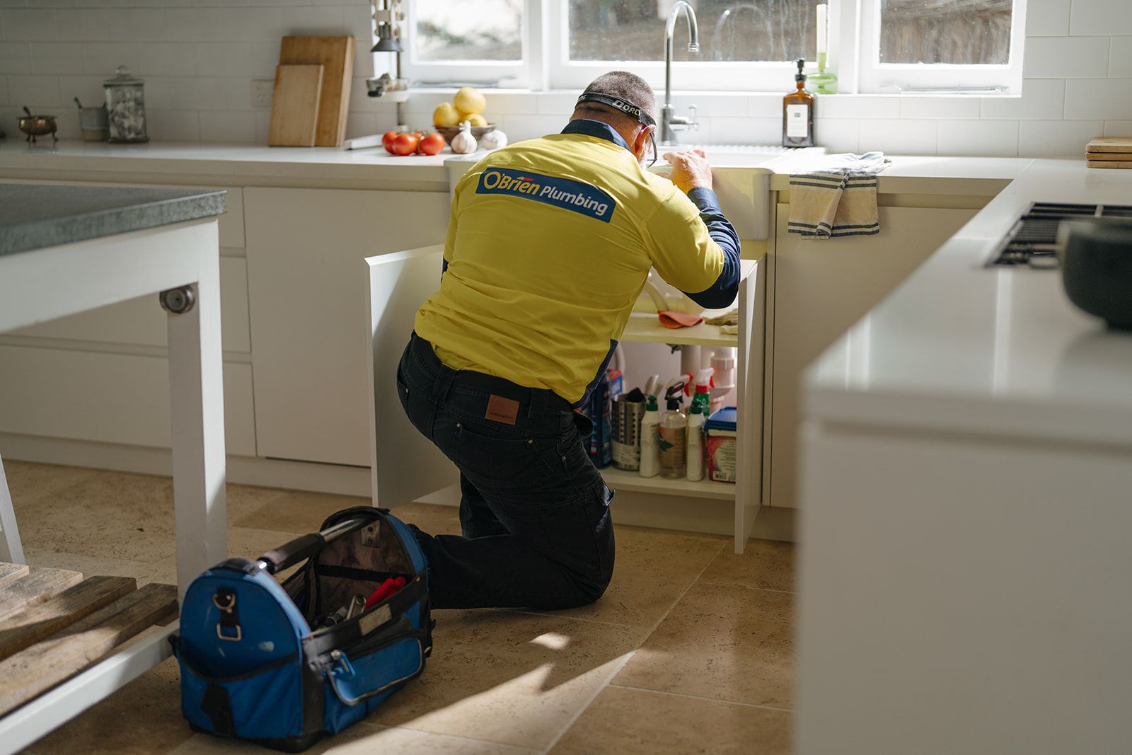 An O’Brien plumber working under a kitchen sink