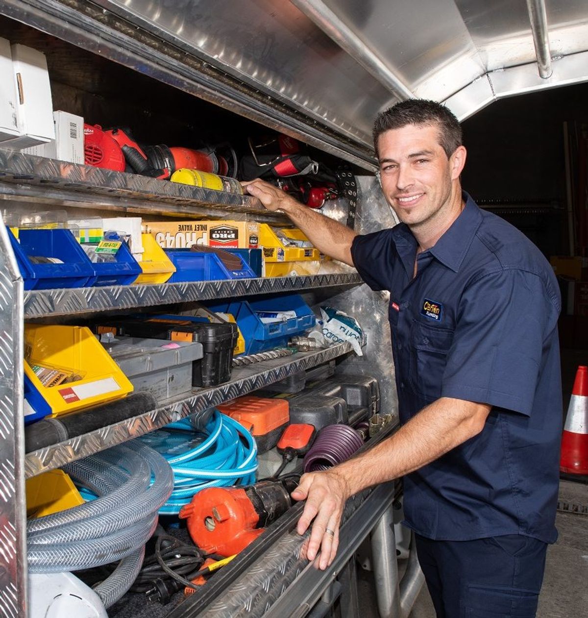 A tradesperson selecting parts from the fitted shelving inside a work van