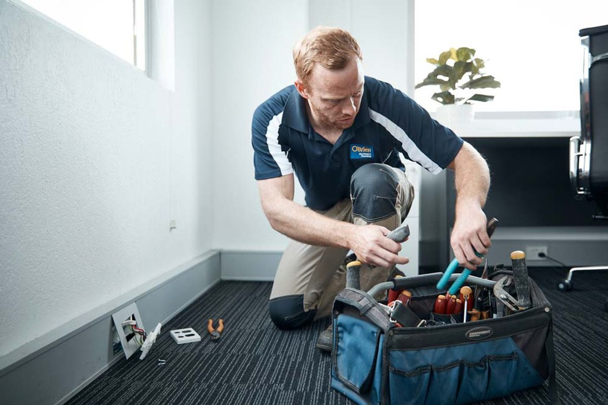 A commercial electrician working at a power outlet in an office