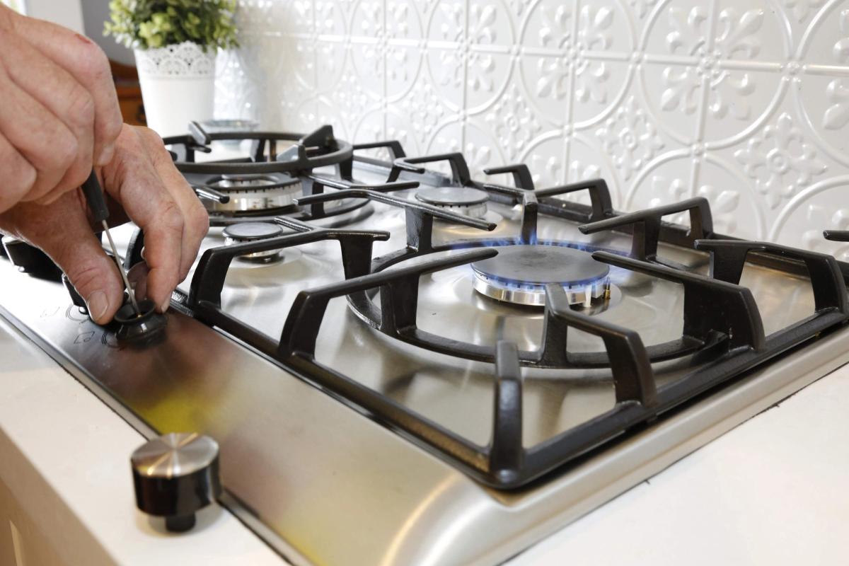 A hand turning on a gas cooktop burner