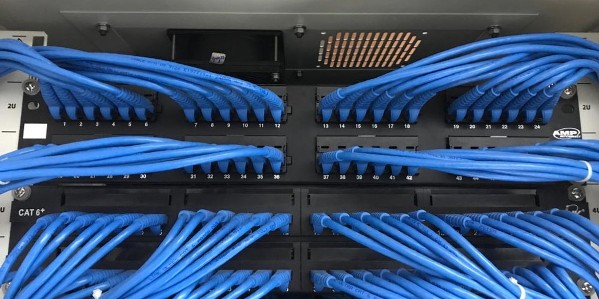 Blue network cables dressed neatly into rack-mounted patch panels