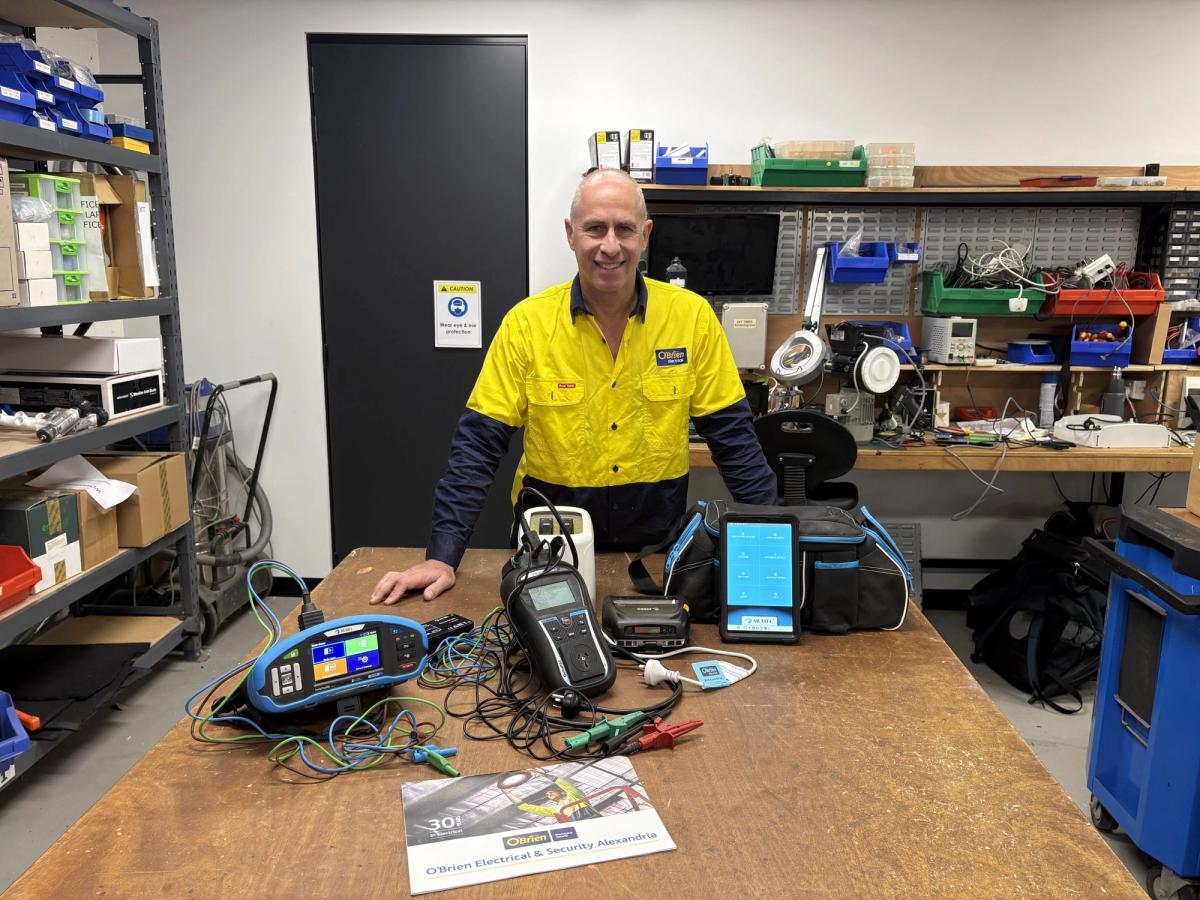 A technician at a workbench with portable appliance testing equipment