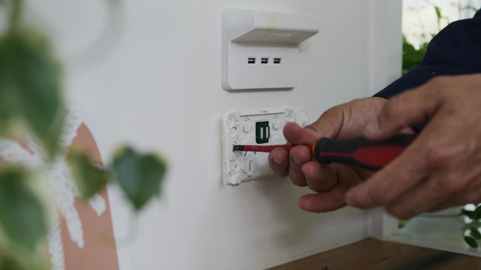 Close-up of hands fitting a power outlet with a screwdriver