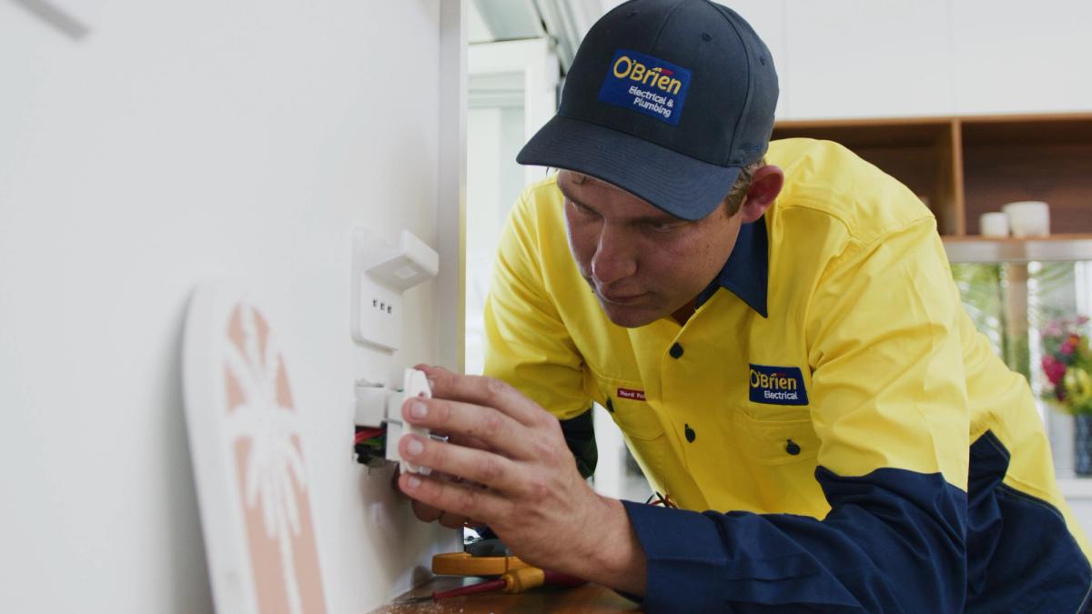 An O’Brien electrician fitting a wall switch in a kitchen