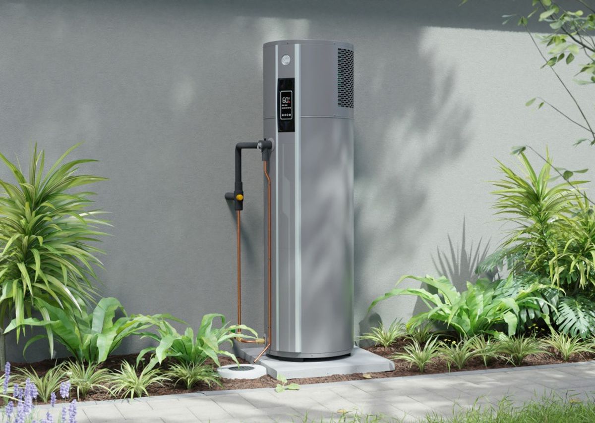 A heat pump hot water cylinder installed outside against a rendered wall