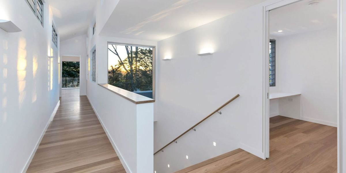 A white hallway lit by wall lights at dusk