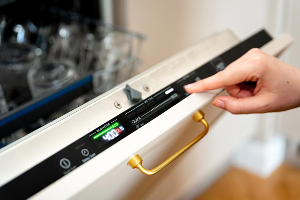 A hand setting the eco cycle on a dishwasher control panel