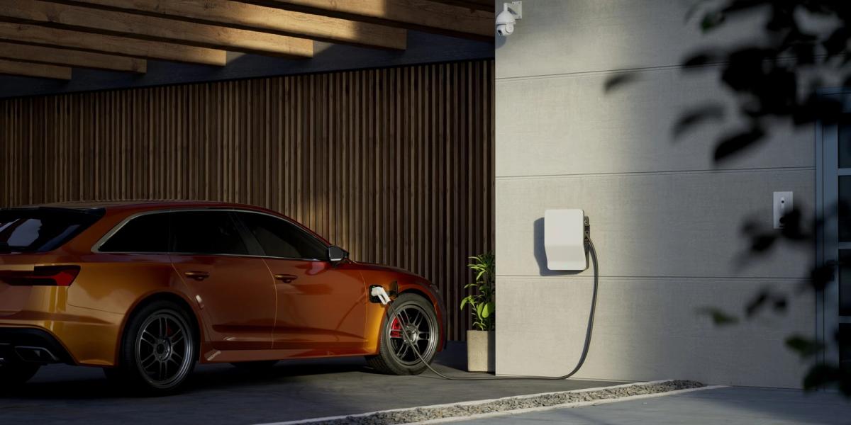 A car parked beside a wall-mounted EV charger in a garage