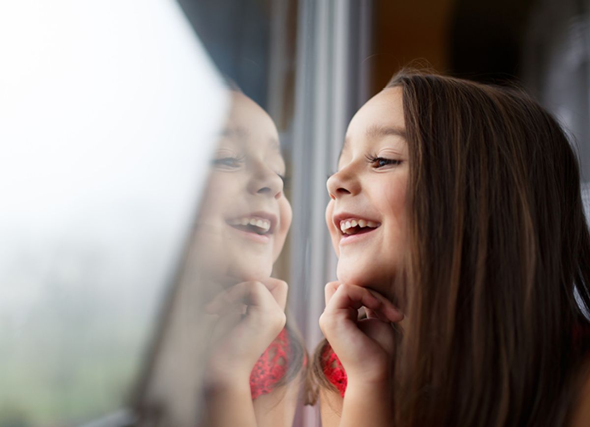 A child smiling beside a window at home
