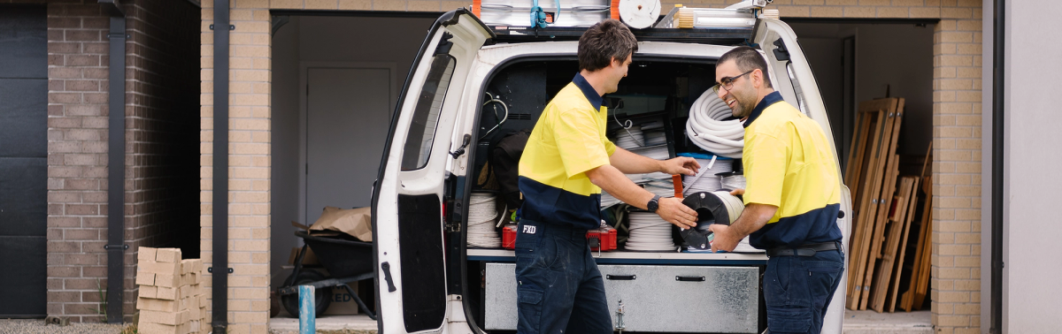 Two O’Brien electricians working at the open back of a van